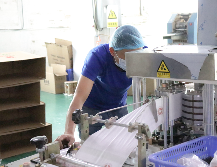 Работник по контролю качества проверяет процесс производства туалетной бумаги